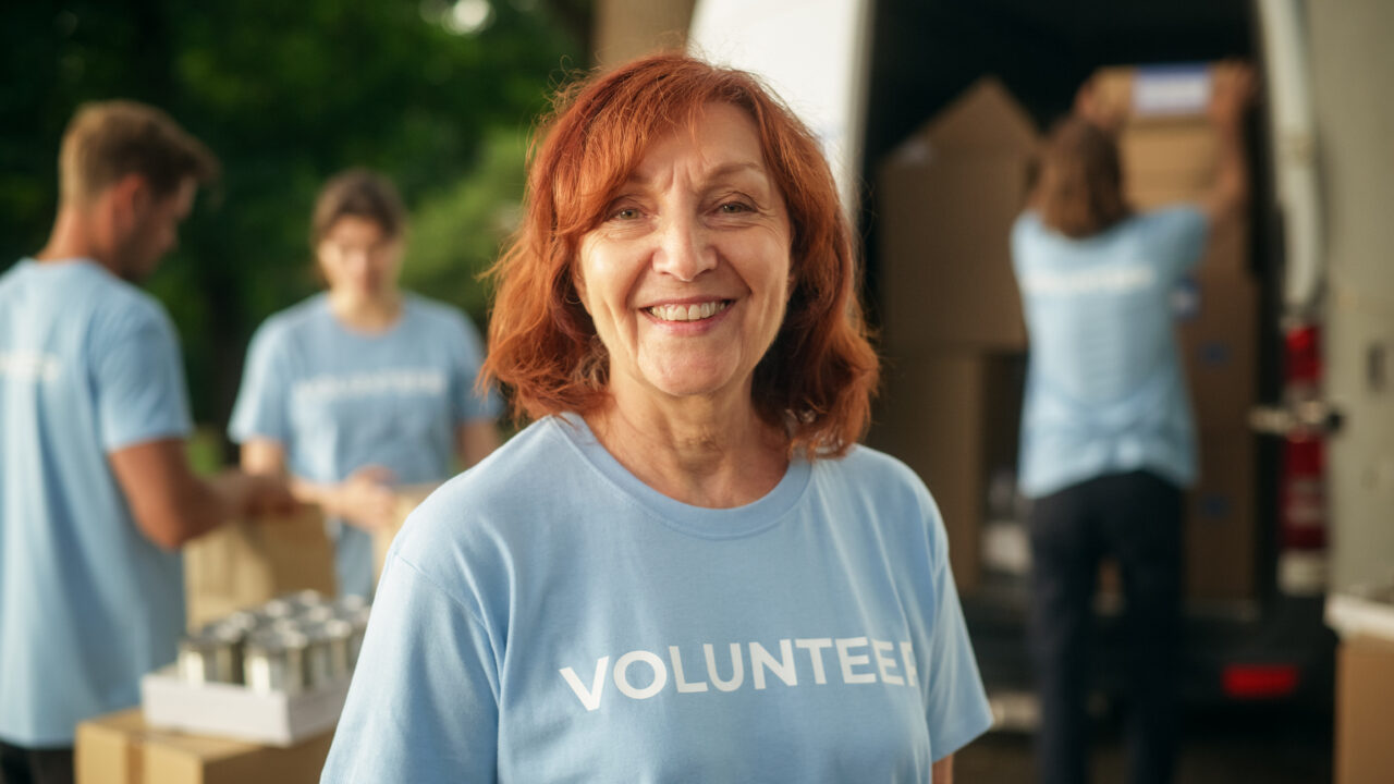Portrait of a Happy Helpful Older Female Volunteer. Adult Woman in Blue T-Shirt, Smiling, Looking at Camera.